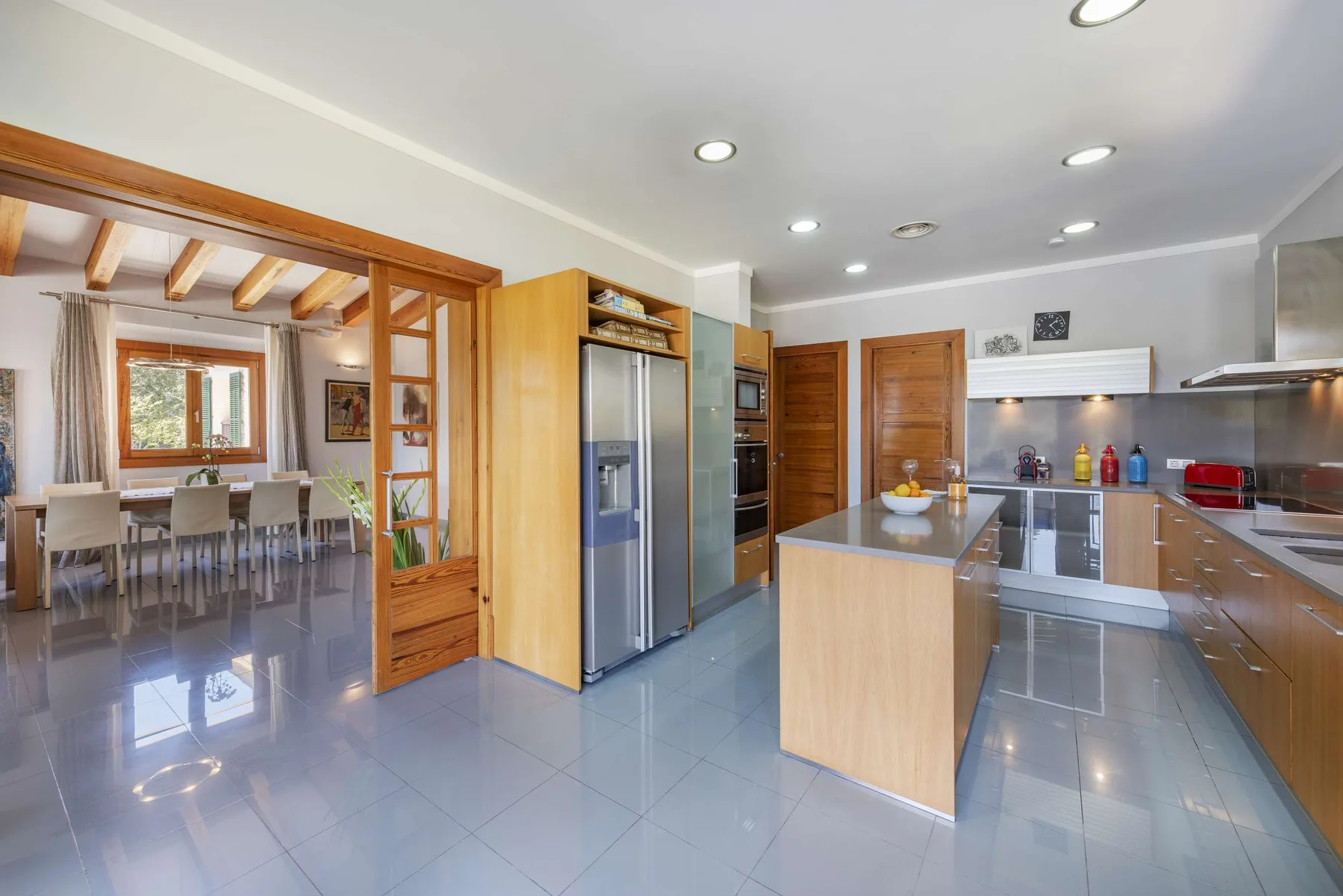 A modern kitchen with a central island opens onto a dining area.