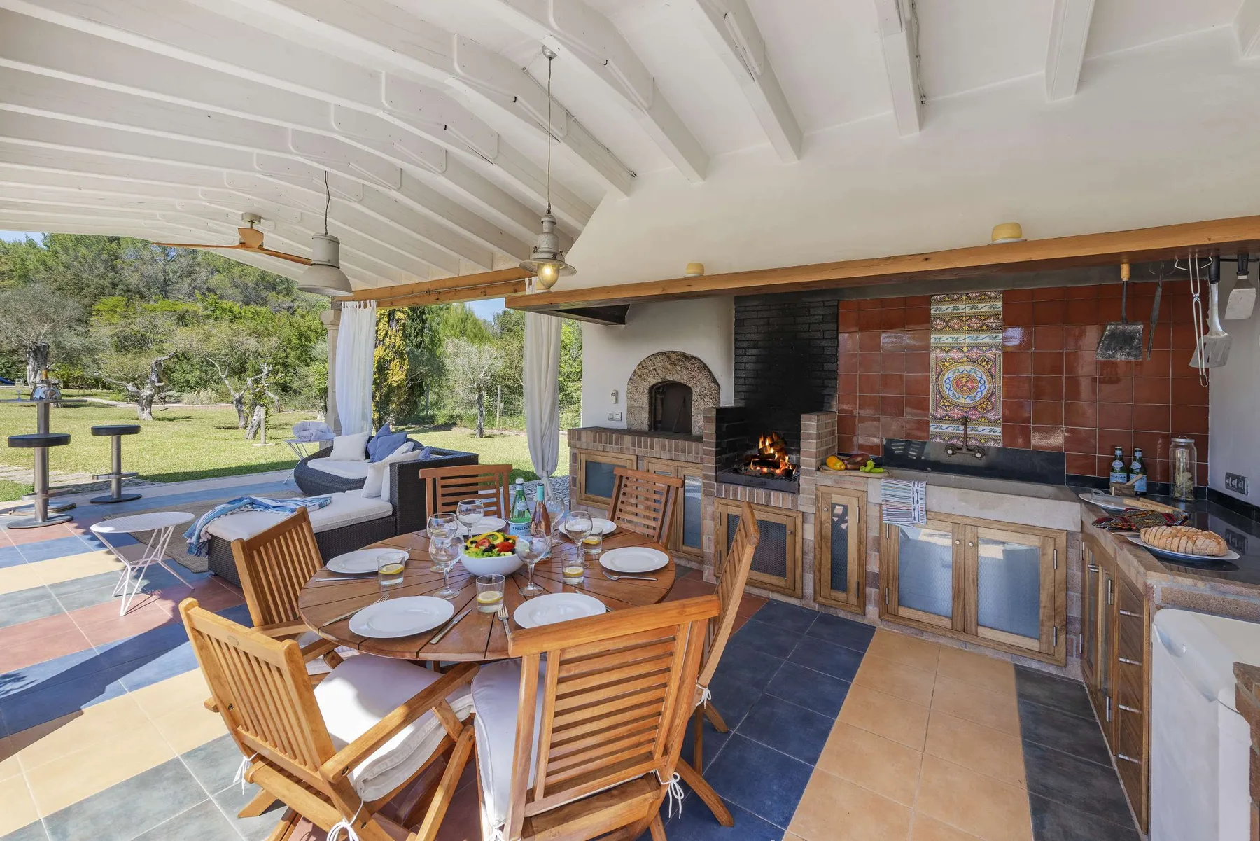 A covered outdoor dining and cooking area opens onto a garden.