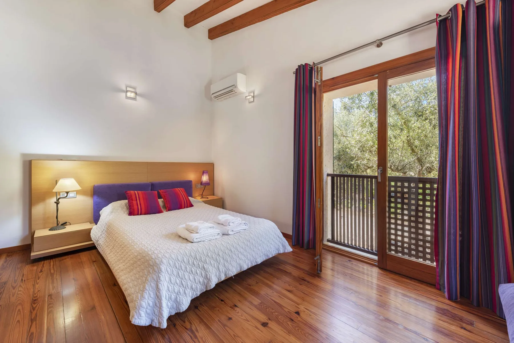A bedroom with a bed beside glass doors opening onto a balcony.