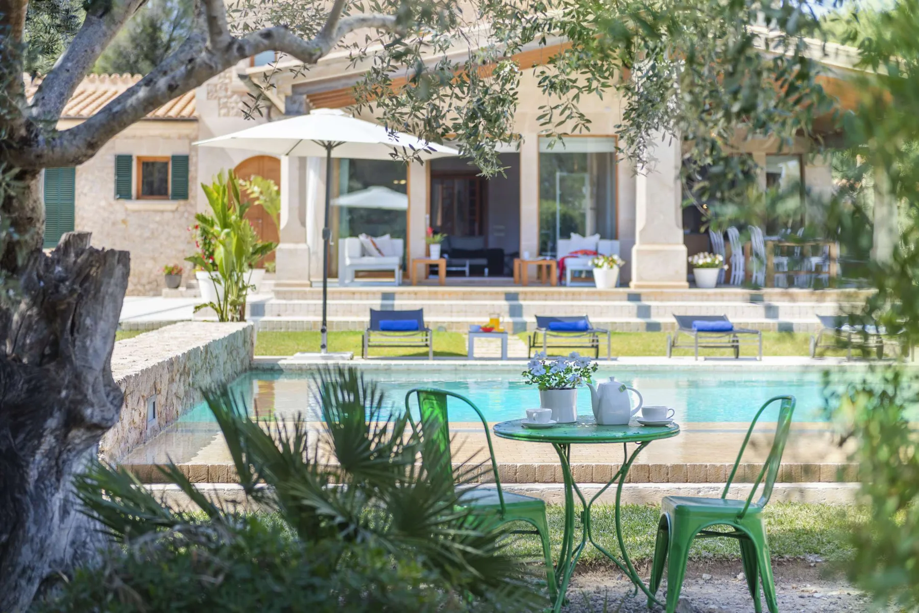 A poolside patio with a small table and seating beside a house.