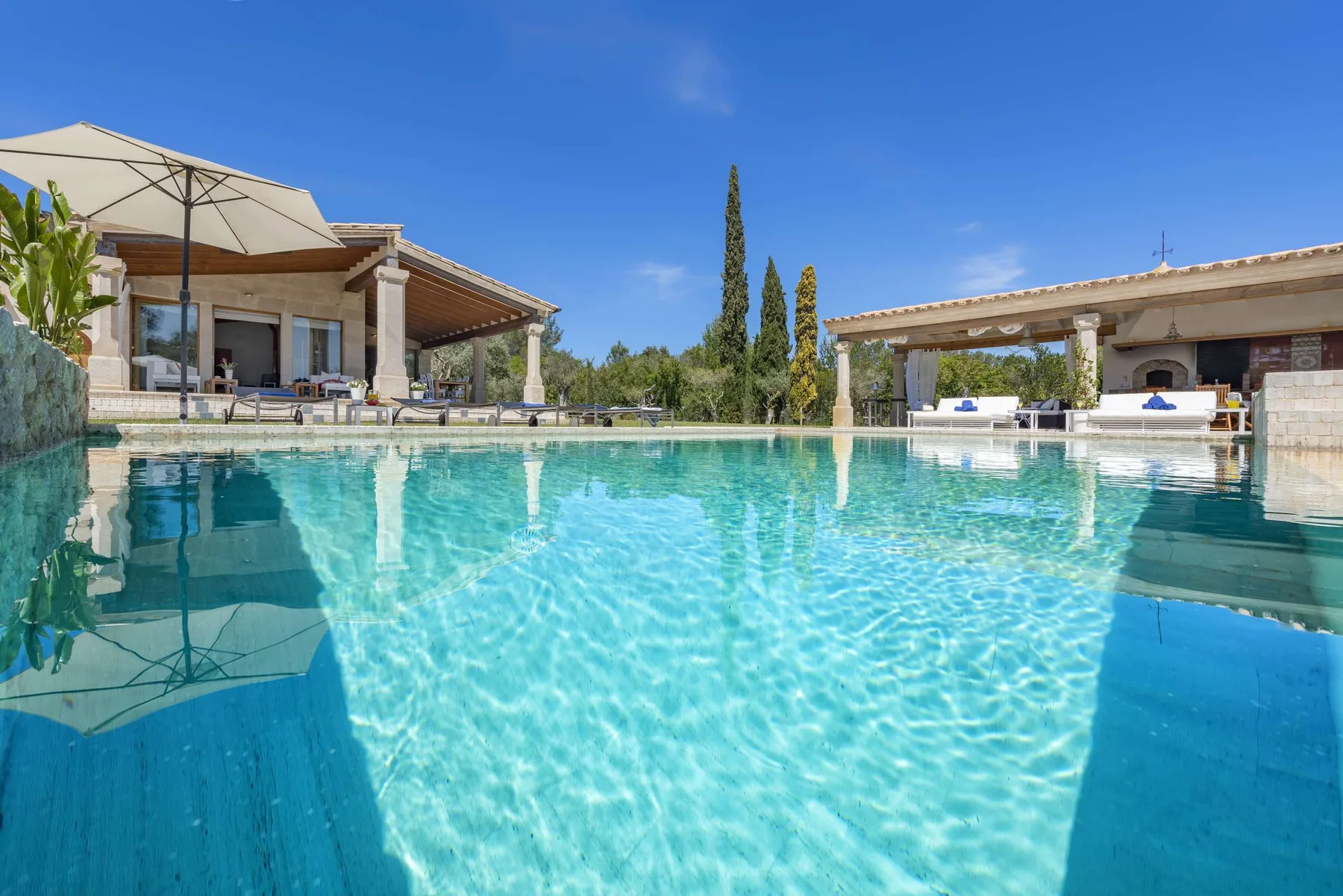 A swimming pool beside a covered patio and outdoor seating.