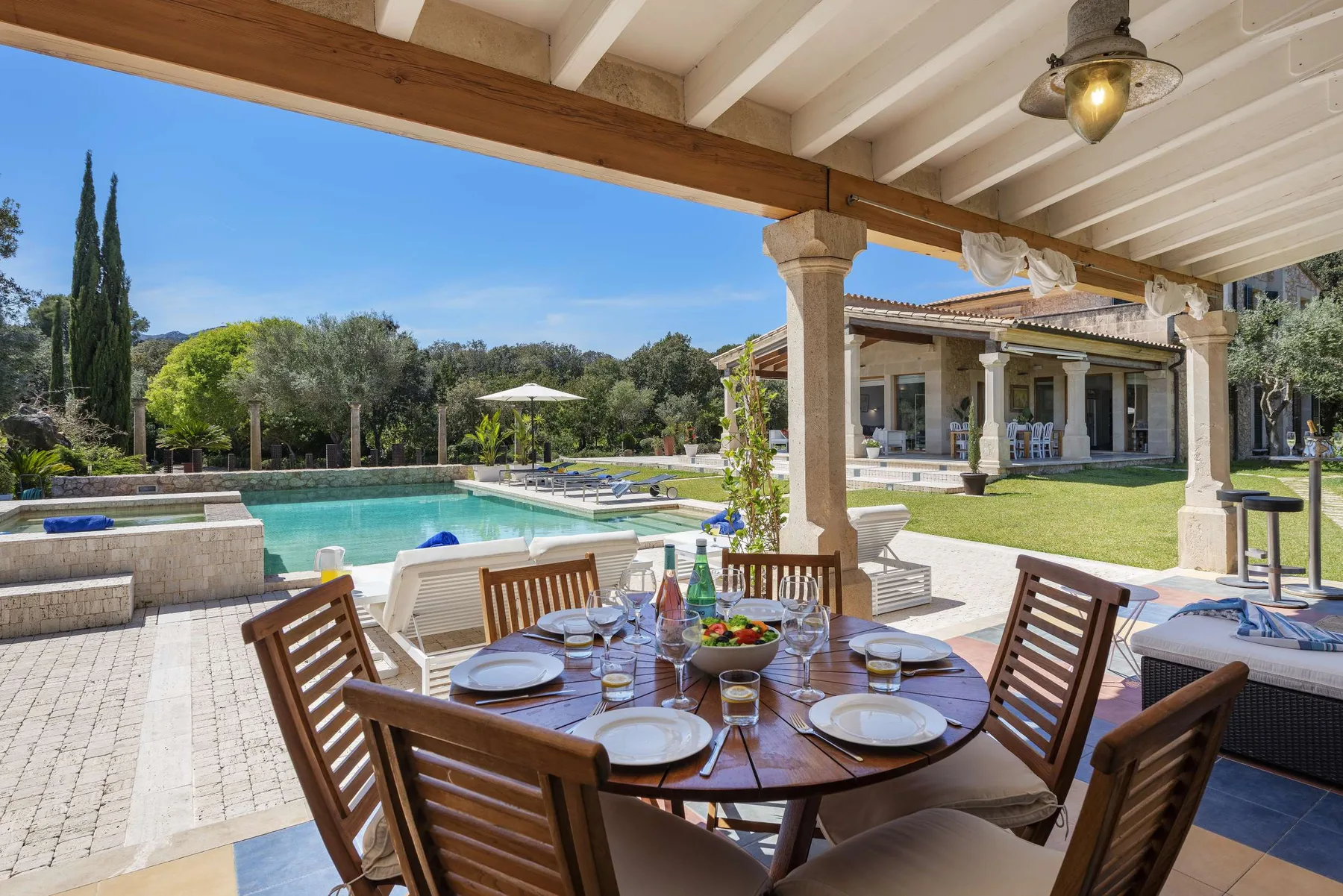 A covered outdoor dining area overlooks a swimming pool and landscaped grounds.