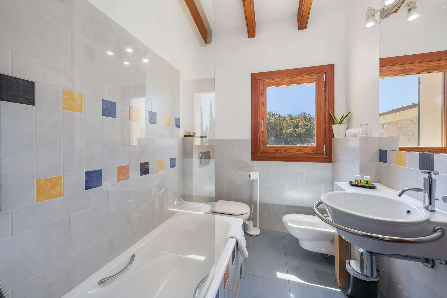 A tiled bathroom with a bathtub, sink, and window.