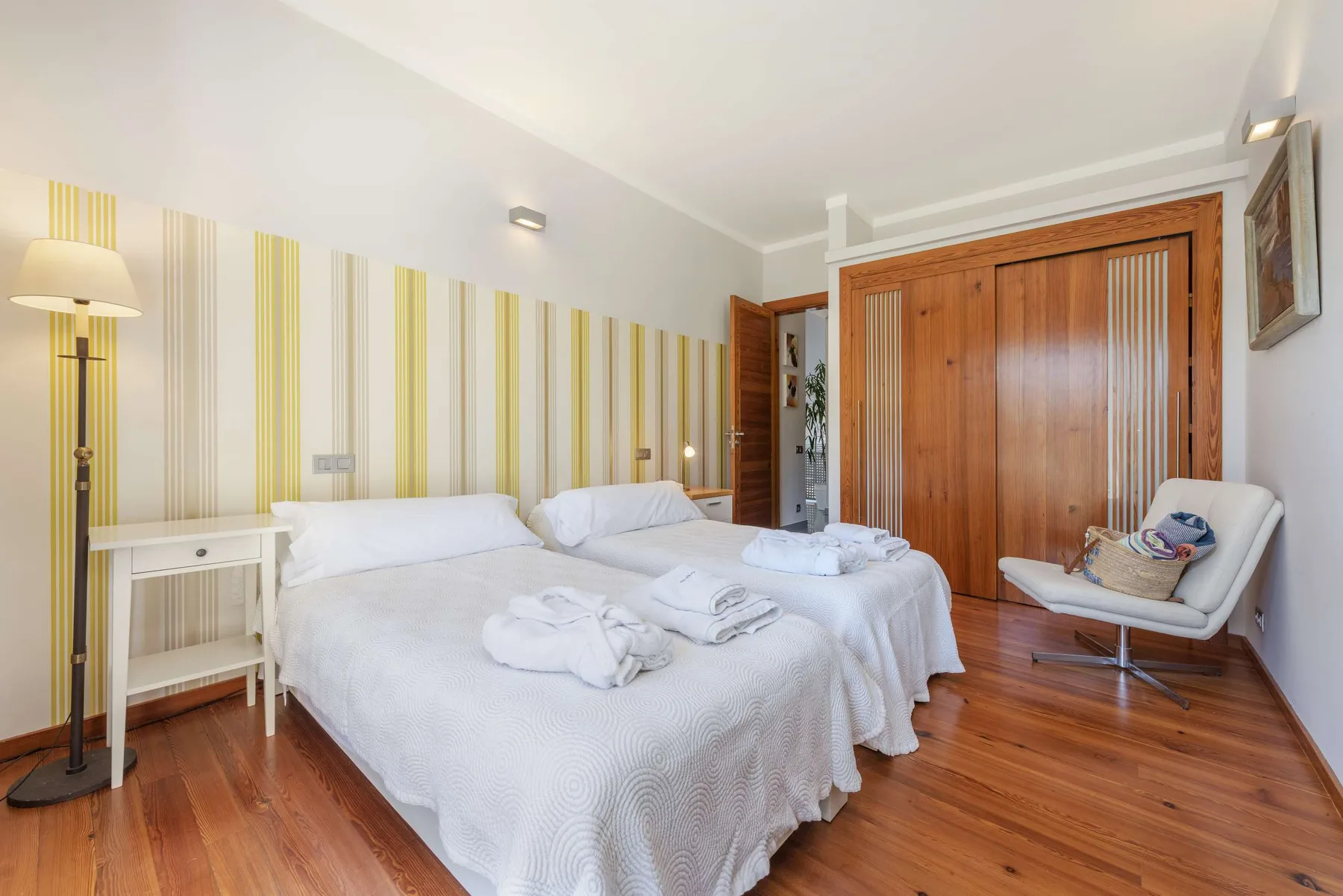 A bedroom with two neatly made beds and a wooden wardrobe.