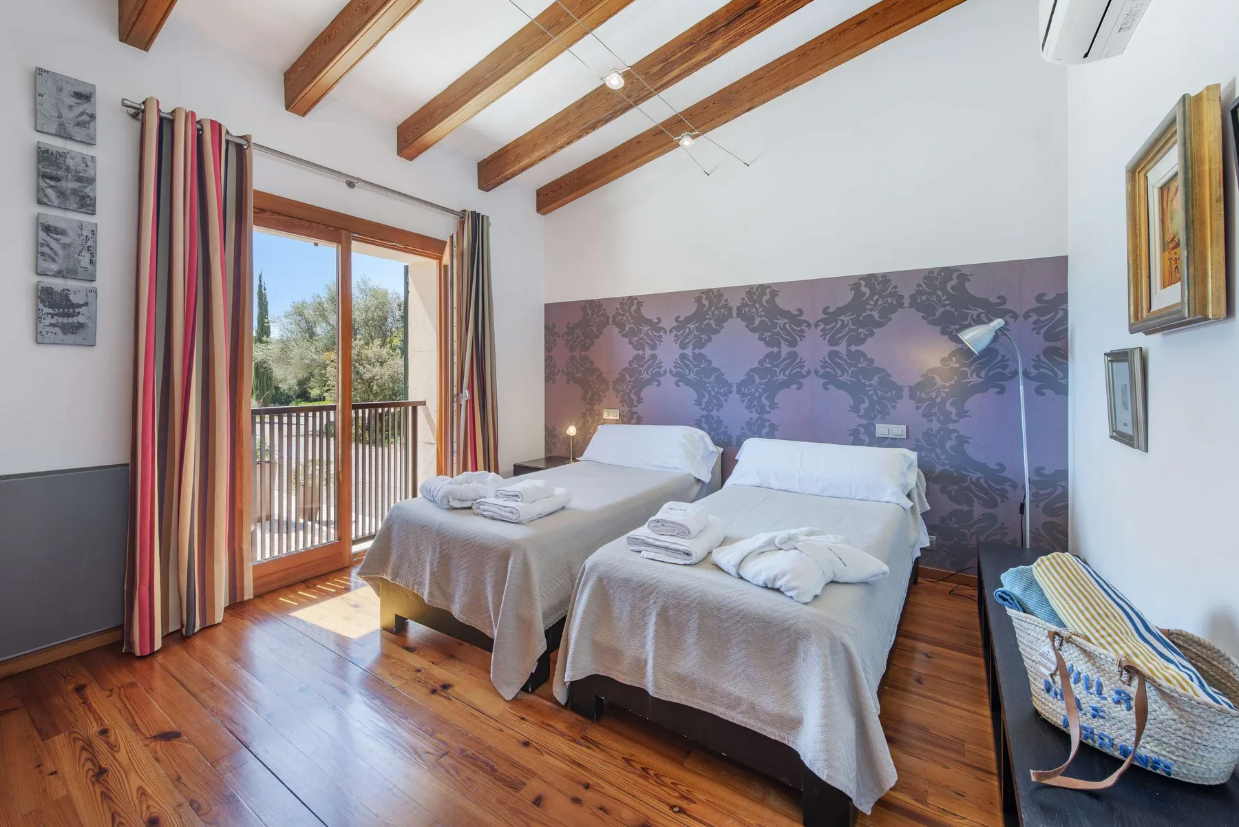 A bedroom with two beds, patterned wallpaper, and a balcony door.