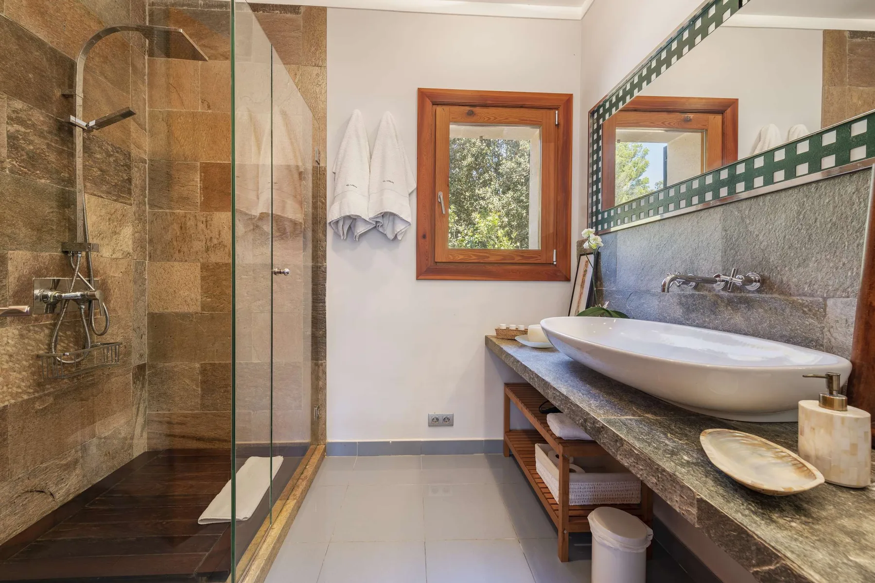 A bathroom with a glass shower and a wide sink counter beneath a mirror.