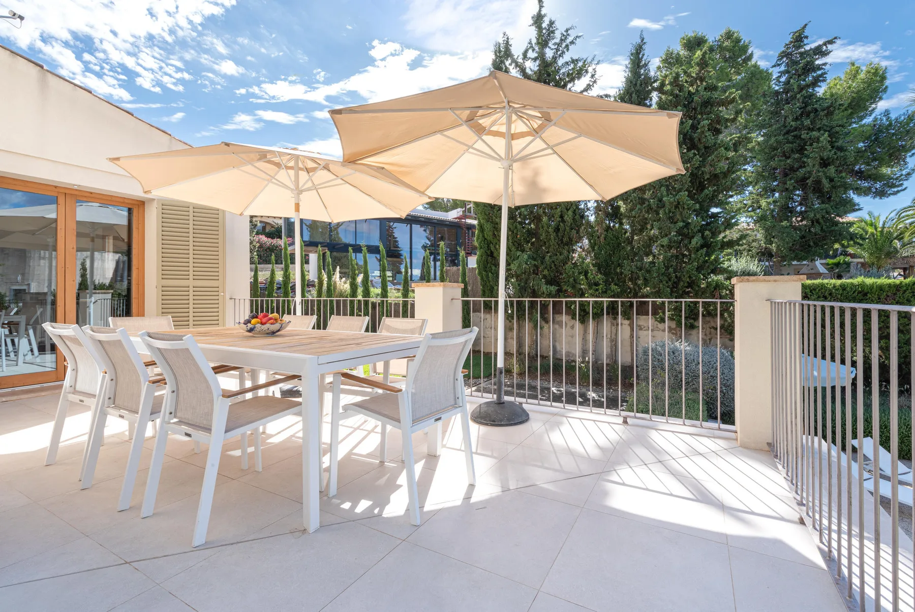 An outdoor dining area with a table, seating, and large umbrellas.