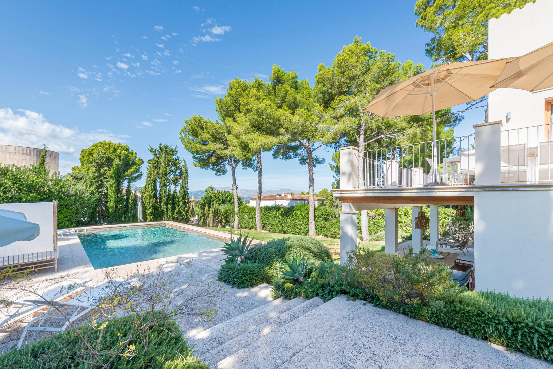 An outdoor swimming pool beside a landscaped patio and a raised terrace.