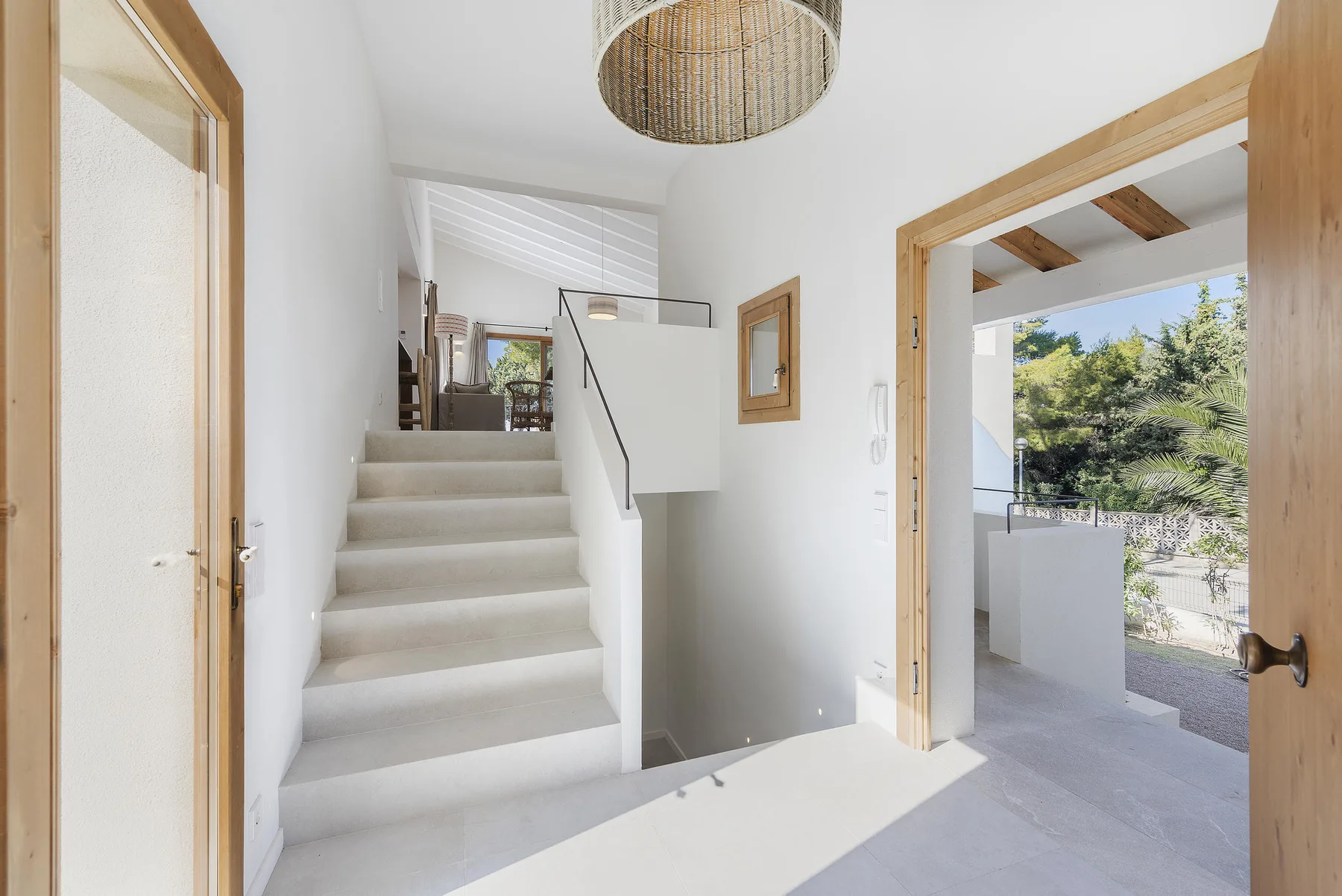A bright interior entryway with a staircase and an open doorway to the outside.