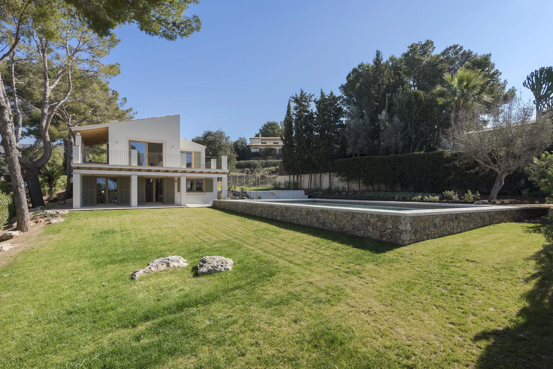 A modern house overlooks a lawn and an outdoor swimming pool.