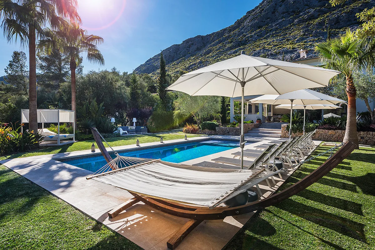An outdoor pool area with lounge seating and large shade umbrellas.