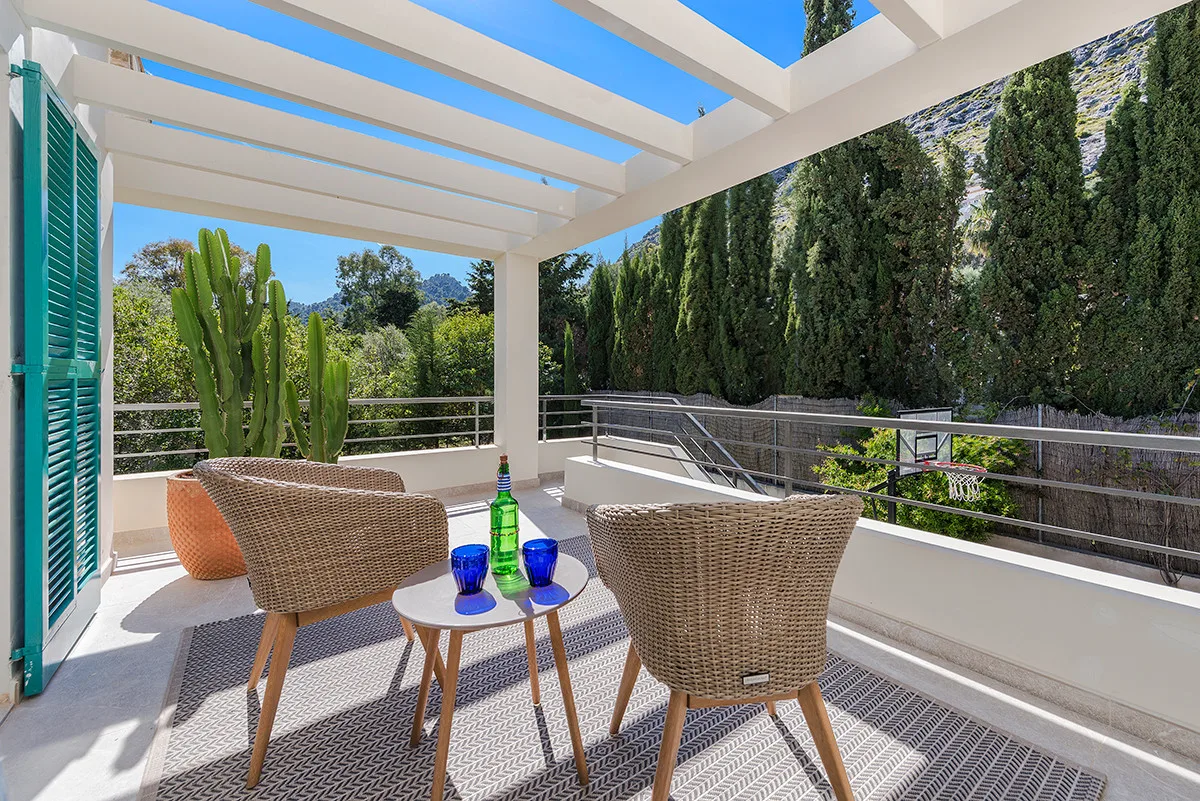 An outdoor covered seating area with woven chairs and a small table.