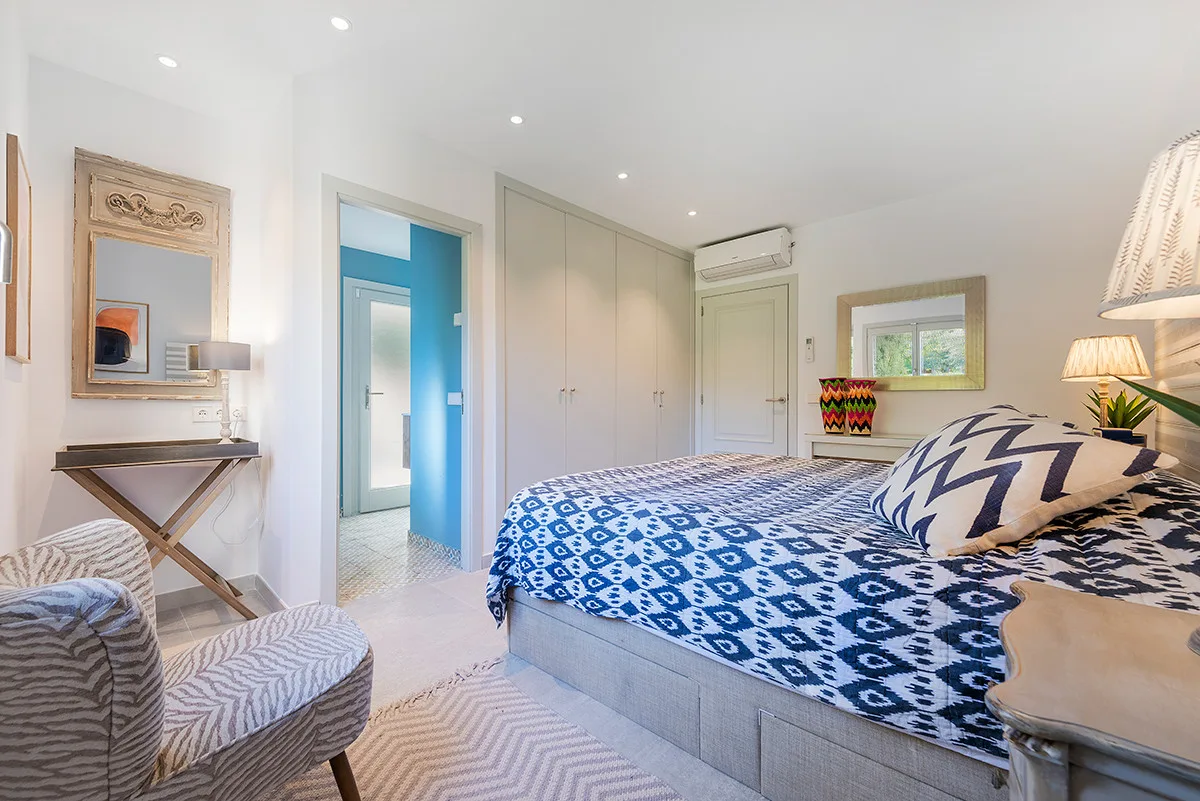 A bright bedroom with a patterned bedspread and a blue doorway.
