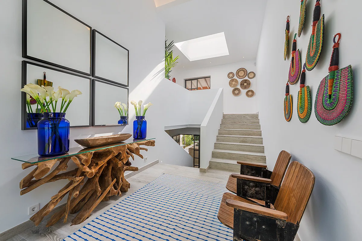 A bright stairway and sitting area with colorful woven wall decorations.
