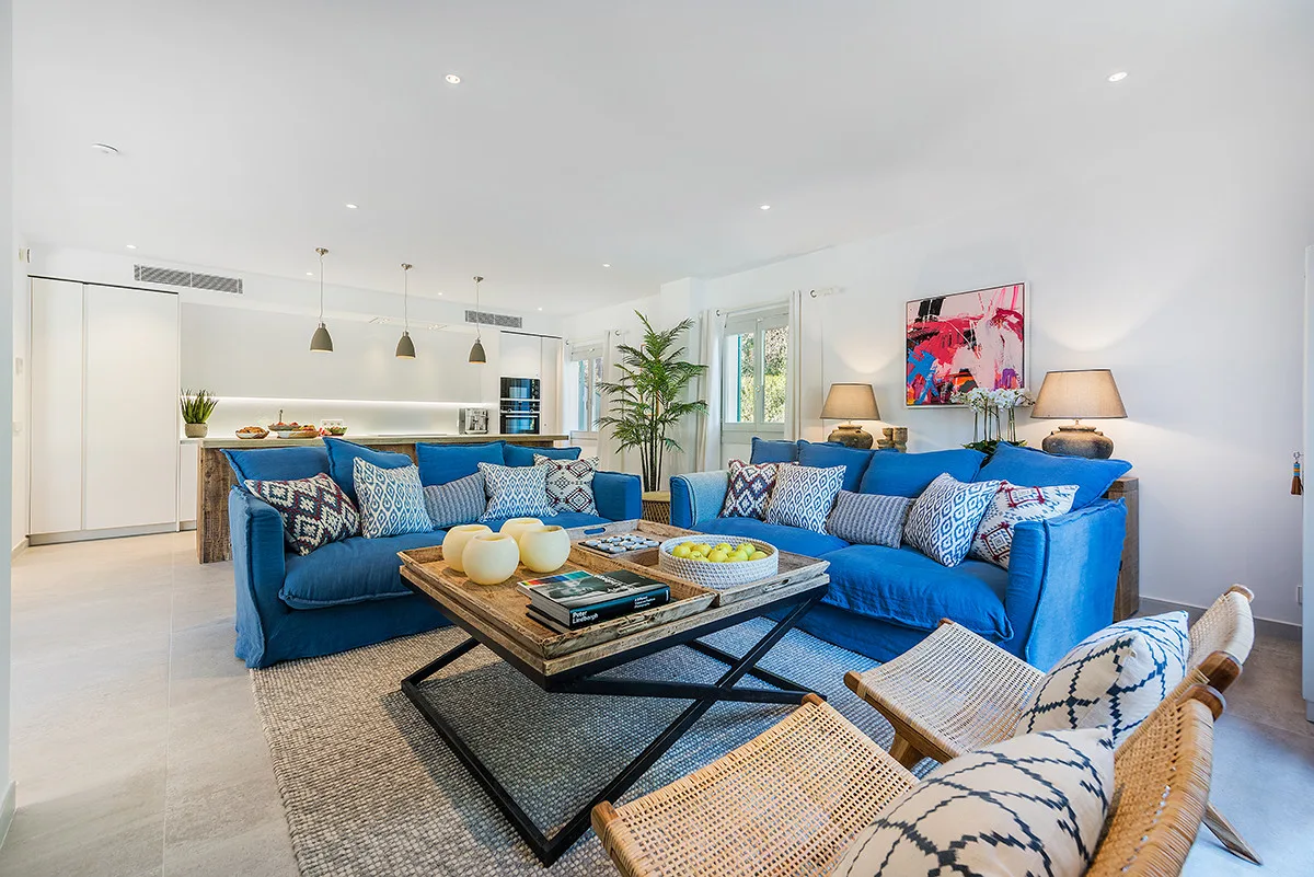 A bright living room features blue seating around a low coffee table.