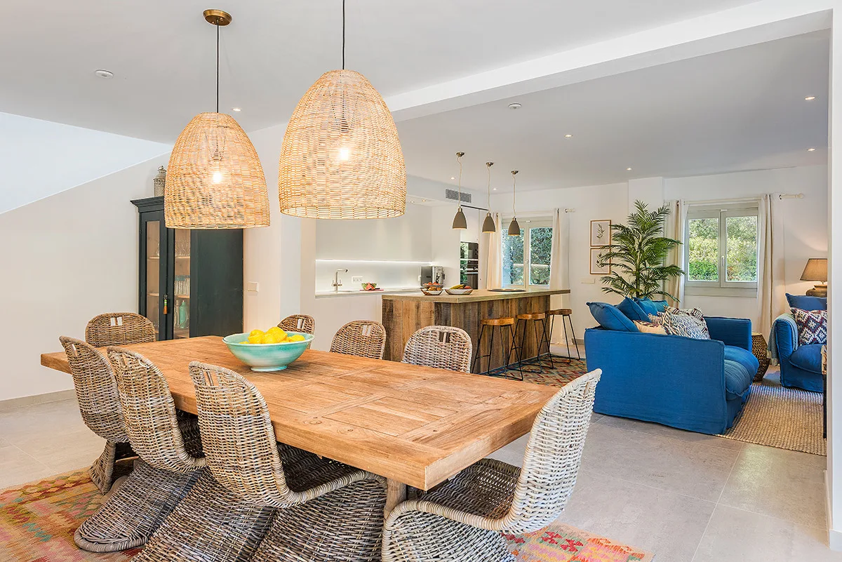 An open-plan dining and living area with a wooden dining table and blue seating.
