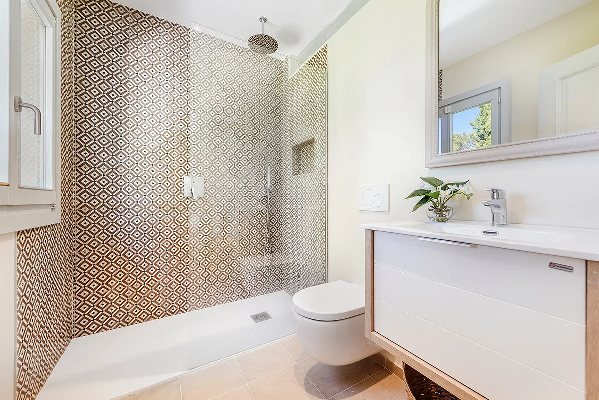 A bright bathroom with a walk-in shower, toilet, and vanity.