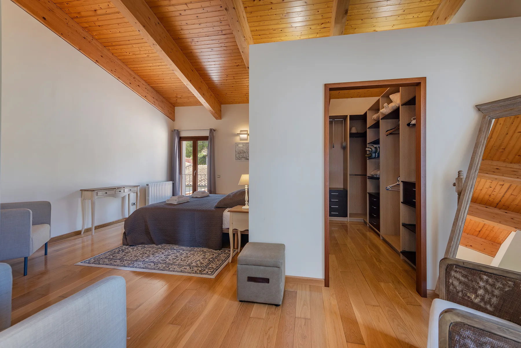 A bedroom with a bed, seating, and an open walk-in closet.