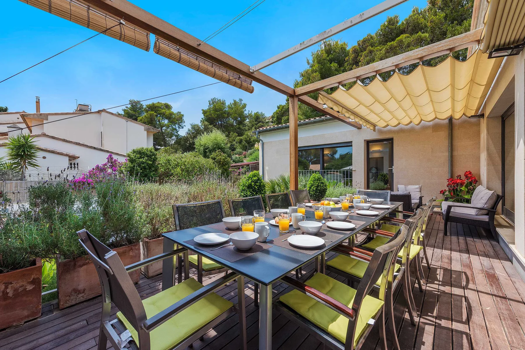 An outdoor dining area with a long table and chairs beneath a canopy.