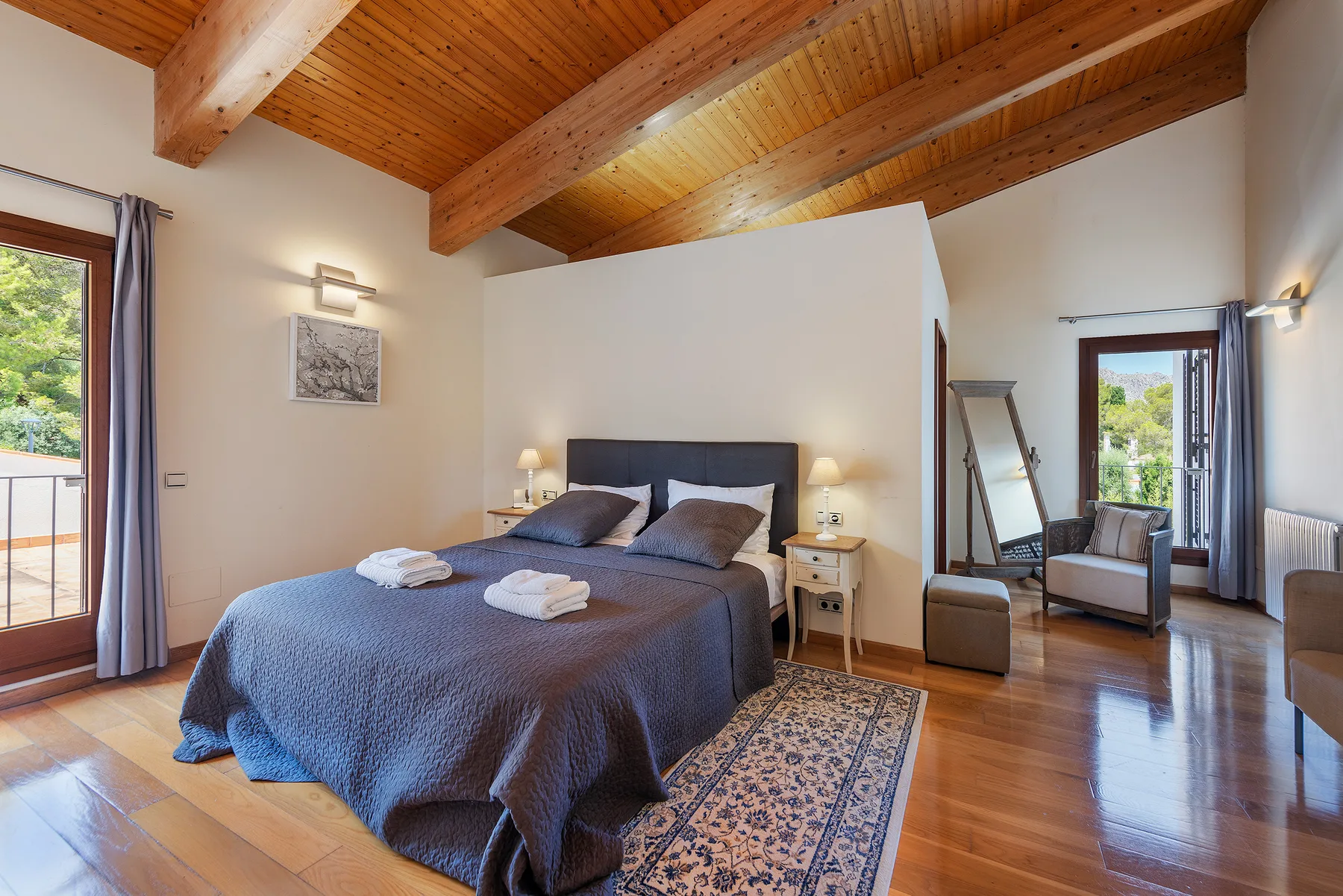 A bedroom with a large bed, bedside tables, and exposed wooden ceiling beams.