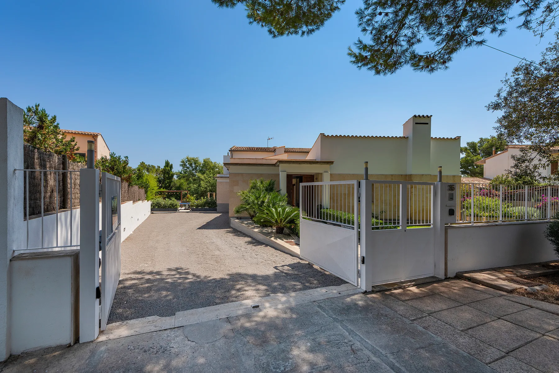 A paved driveway leads to a gated residential building.