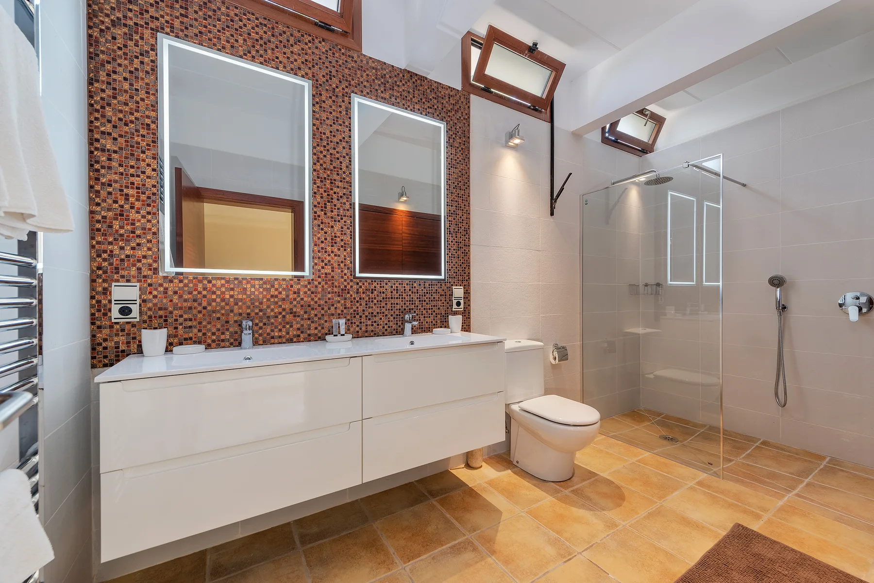 A spacious bathroom with a double sink vanity, mirrors, and a glass shower.