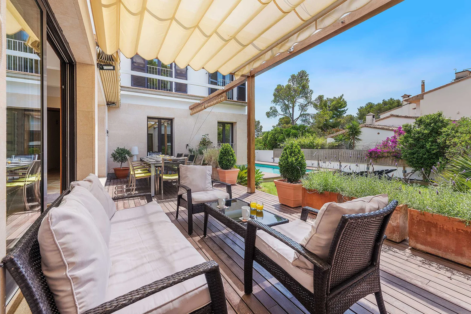 An outdoor patio with cushioned seating beneath a fabric awning.