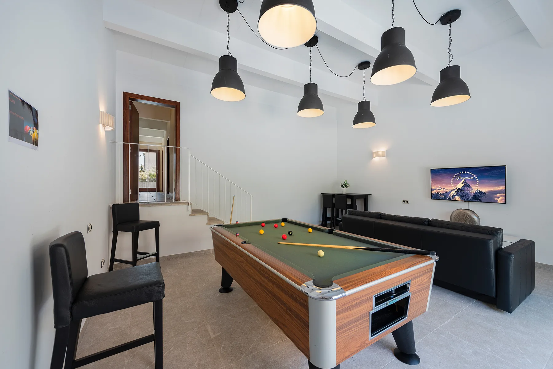 A recreation room with a pool table and seating.