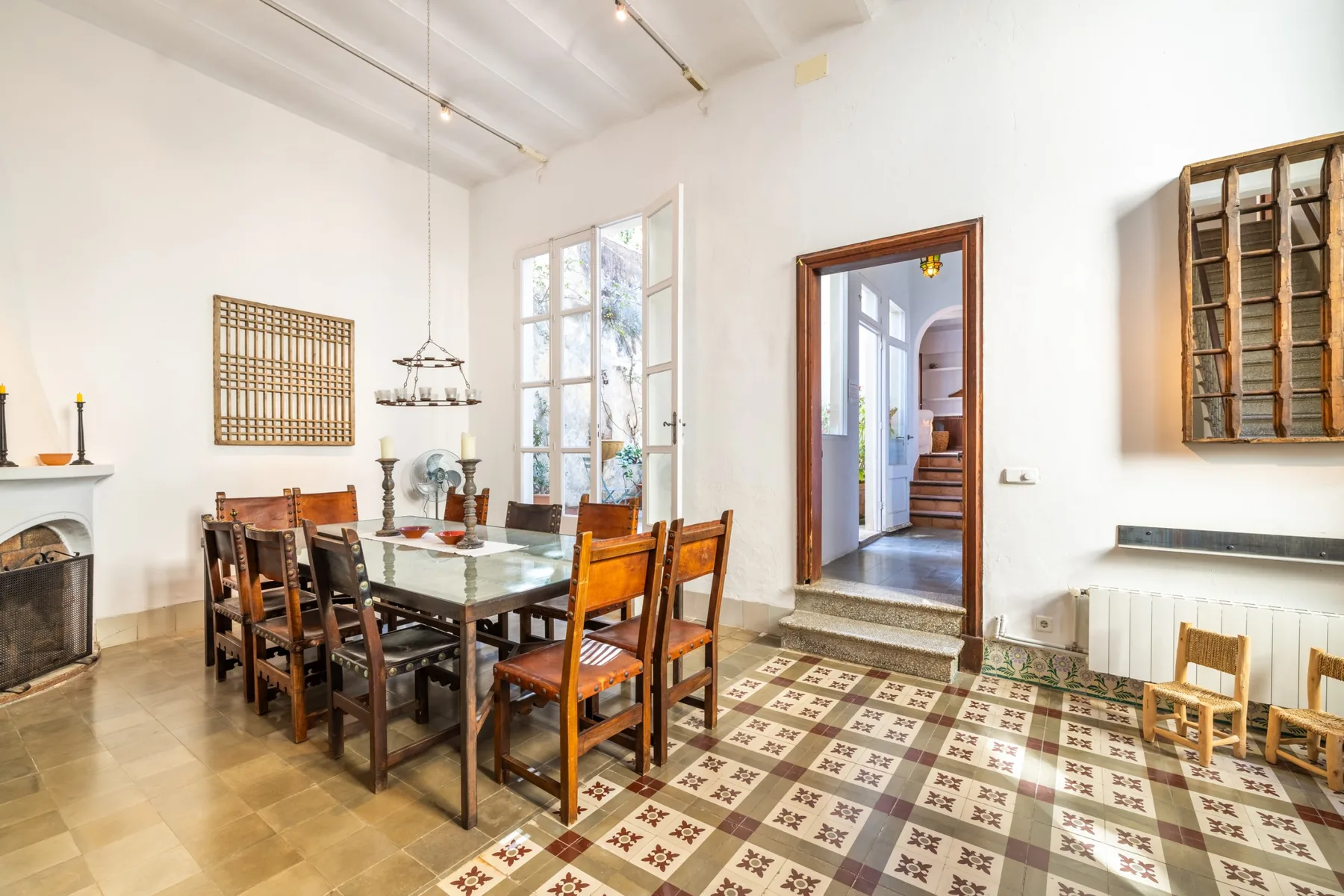 Un comedor luminoso con una gran mesa de madera junto a ventanas altas.