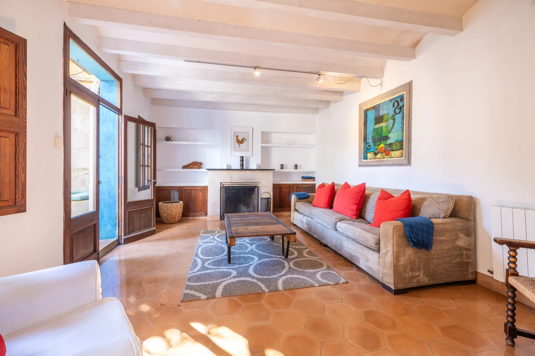 Una sala luminosa con chimenea, asientos y una alfombra estampada.