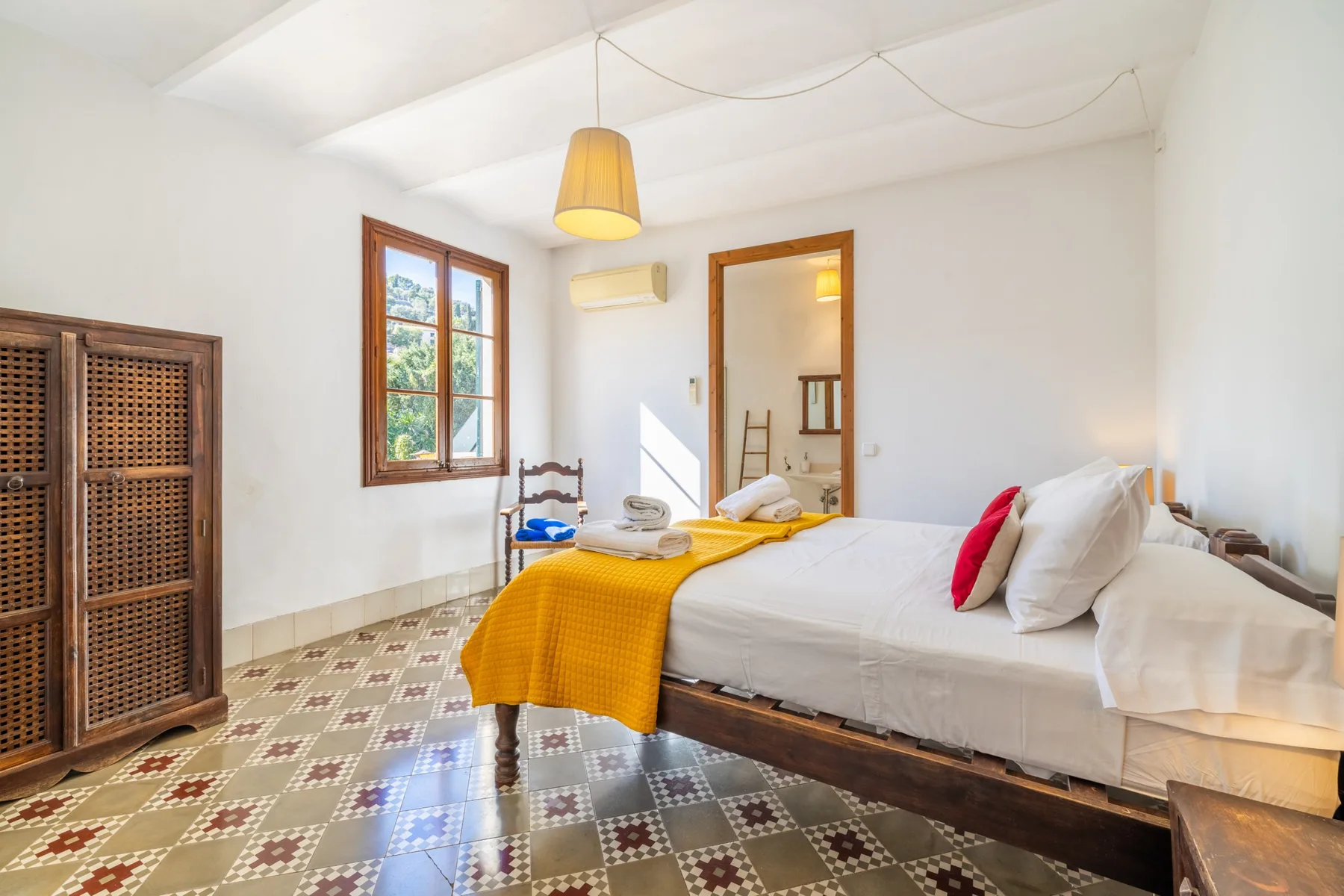 Un dormitorio luminoso con una cama grande y una manta amarilla mostaza.