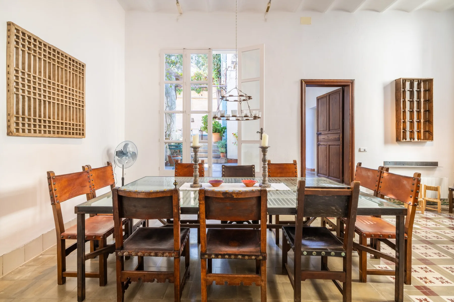 Un comedor con una mesa larga de madera y sillas junto a ventanas altas.