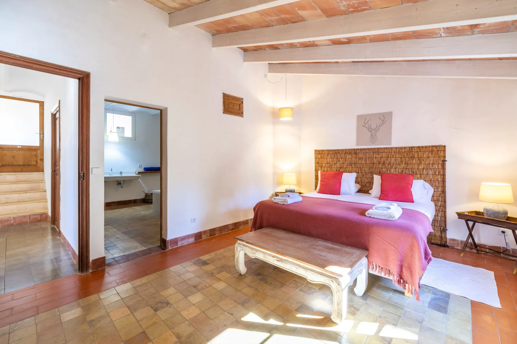 Un dormitorio con una cama, un cabecero tejido y vigas vistas en el techo.