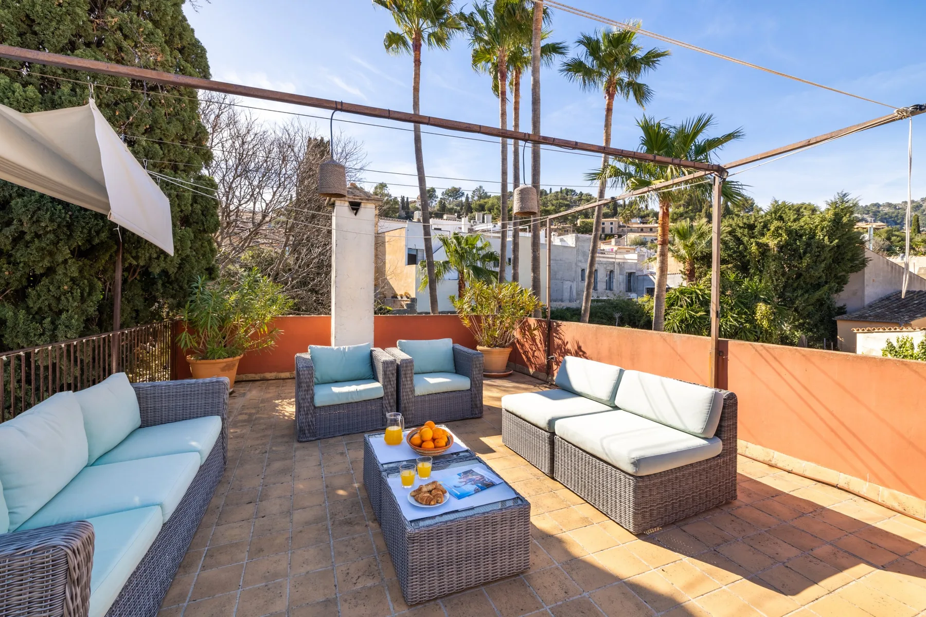 Una zona de estar exterior soleada con asientos acolchados y una mesa baja.