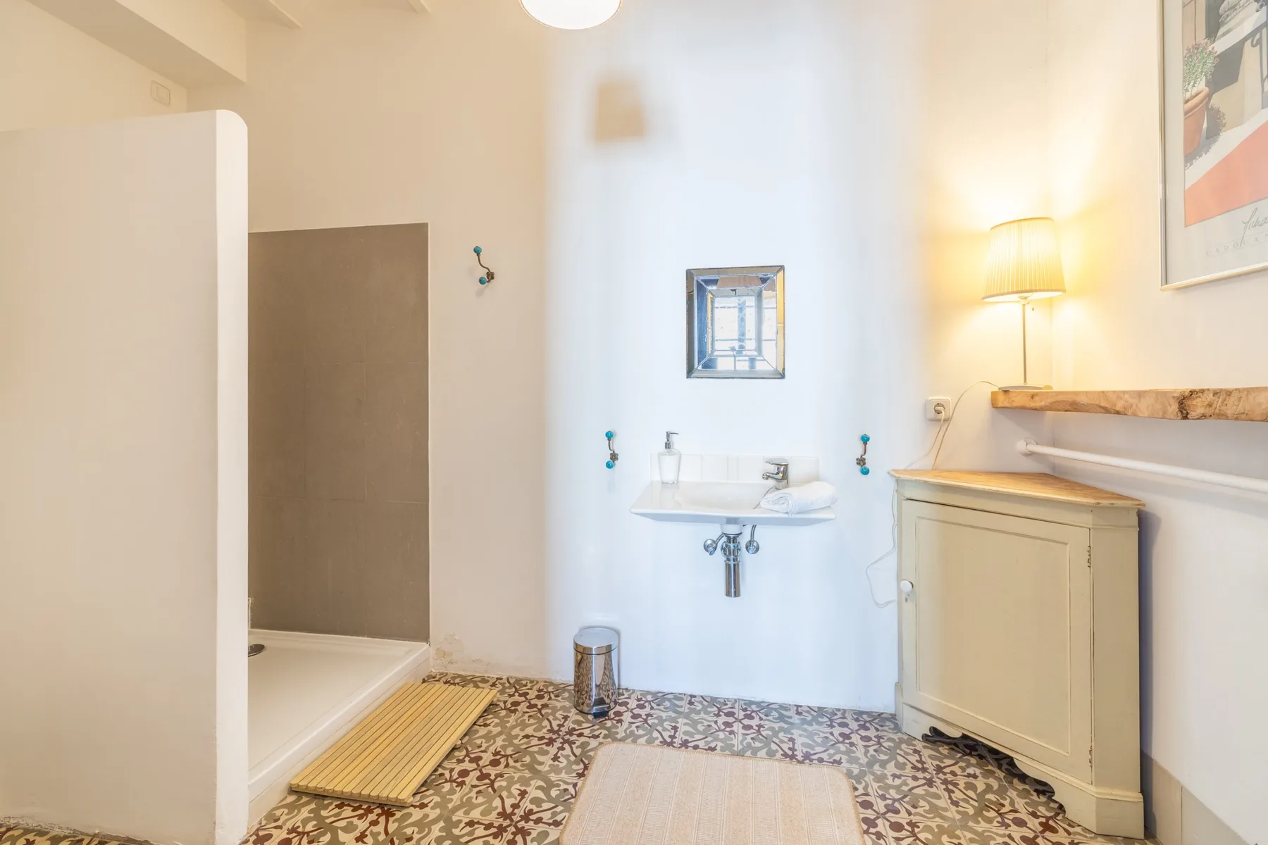 Un baño luminoso con un lavabo de pared y un suelo estampado.