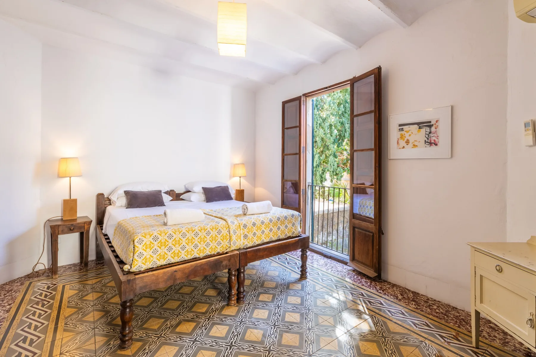 Un dormitorio luminoso con dos camas junto a una puerta abierta a un balcón.