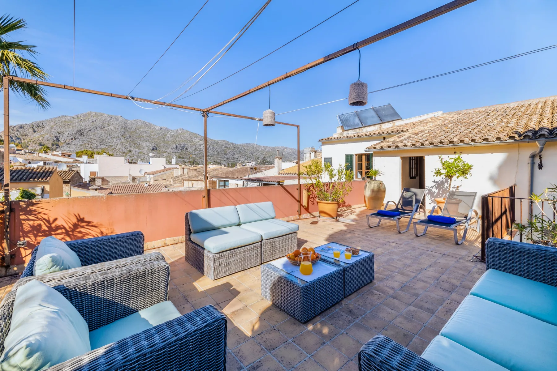 Una terraza soleada en la azotea con asientos al aire libre y vistas a tejados y colinas cercanas.