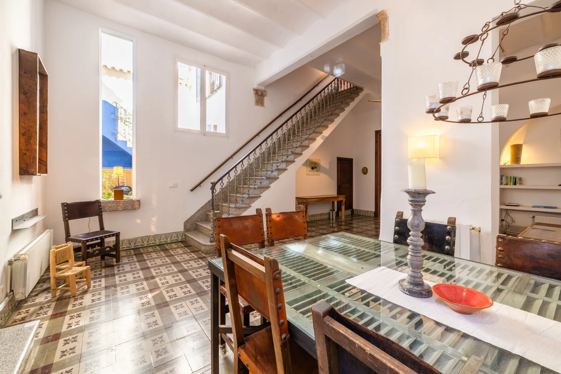 Un comedor con una mesa de vidrio y una escalera al fondo.