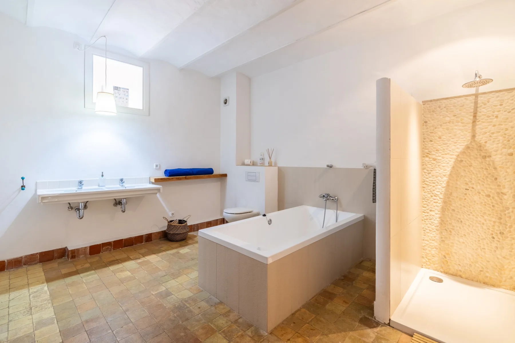 Un baño luminoso con bañera y una zona de ducha abierta.