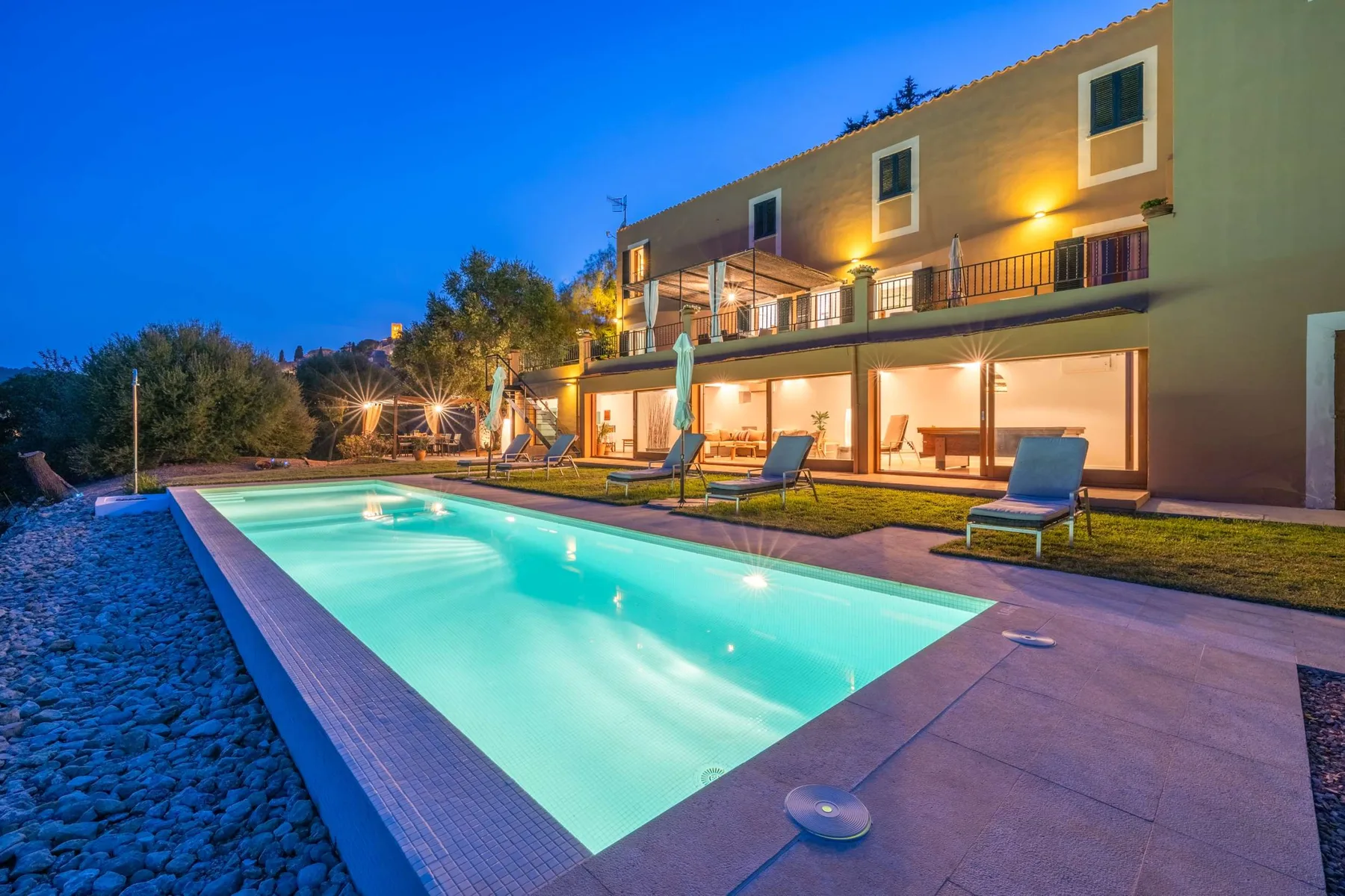 A swimming pool beside a modern building, with outdoor seating along the patio.