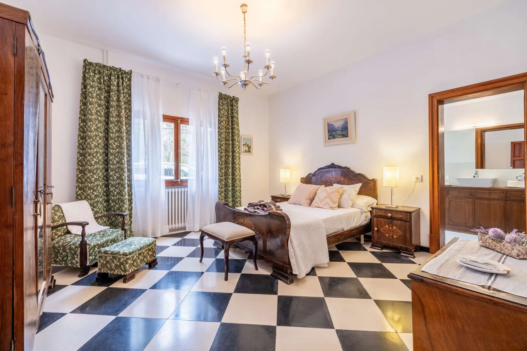 A bedroom with a bed, seating, and a black-and-white checkered floor.