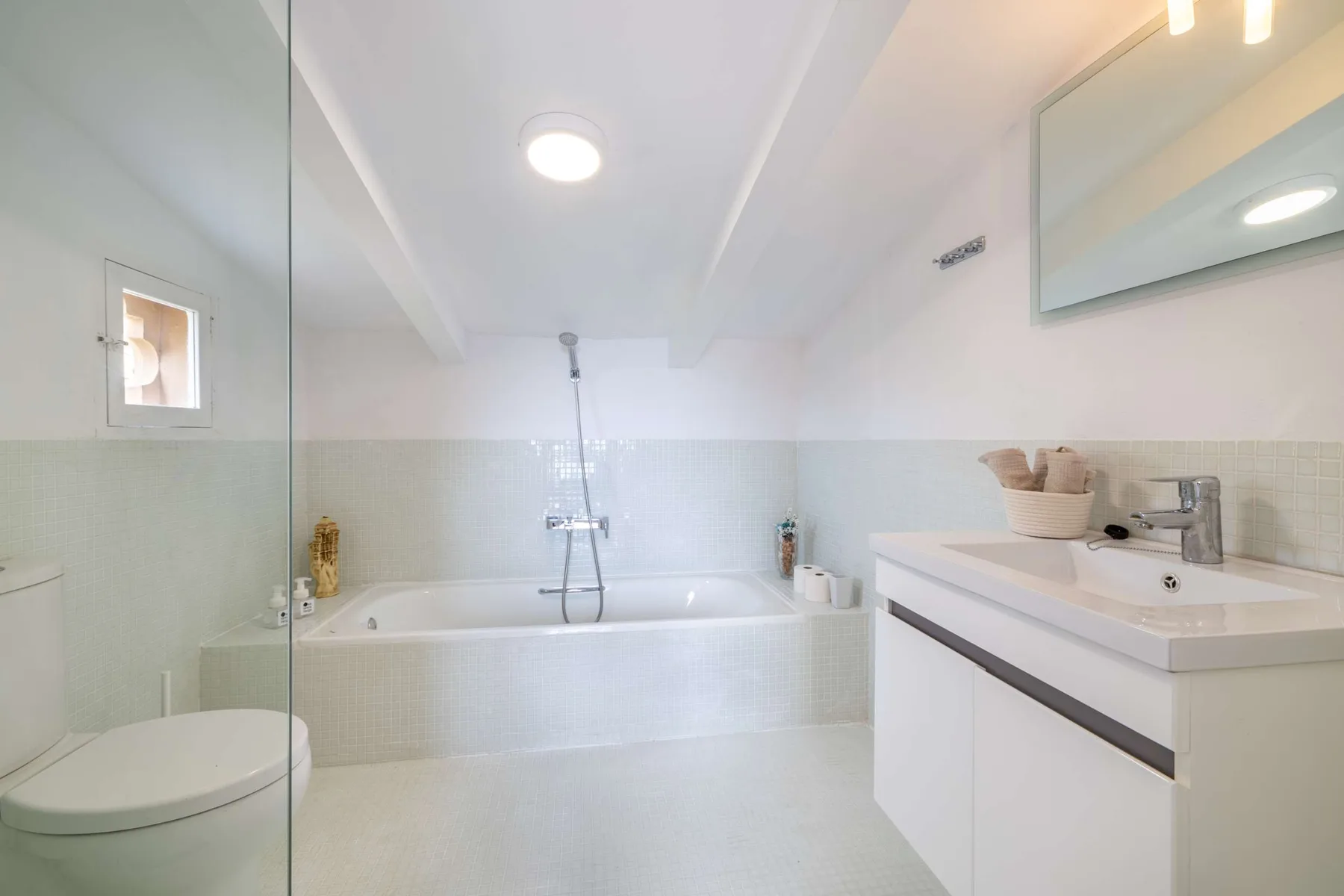 A bright bathroom with a bathtub, shower, and sink vanity.