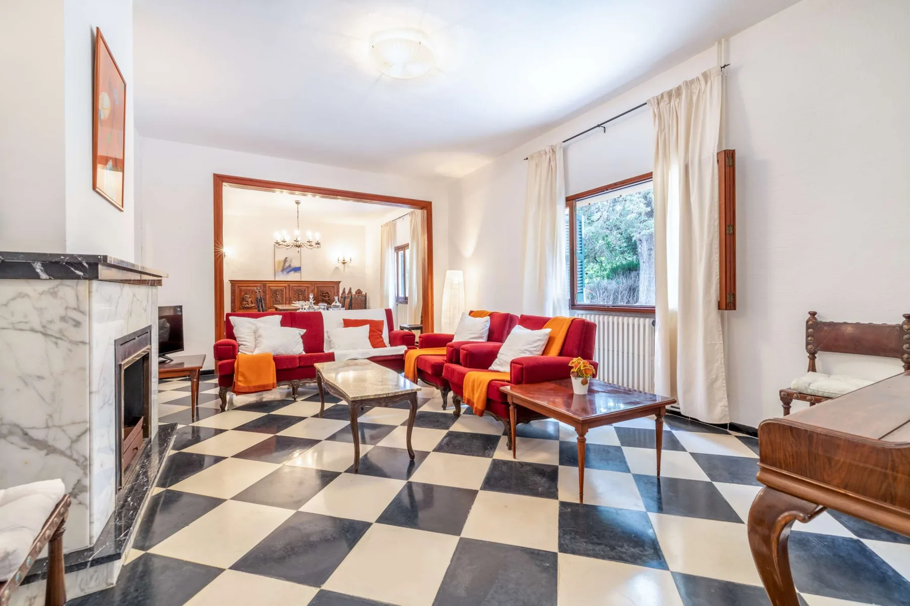 A living room with red seating arranged around a coffee table on a checkerboard floor.