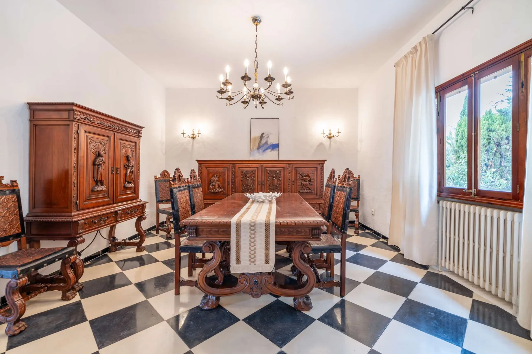 A formal dining room with a long wooden table and patterned tile floor.