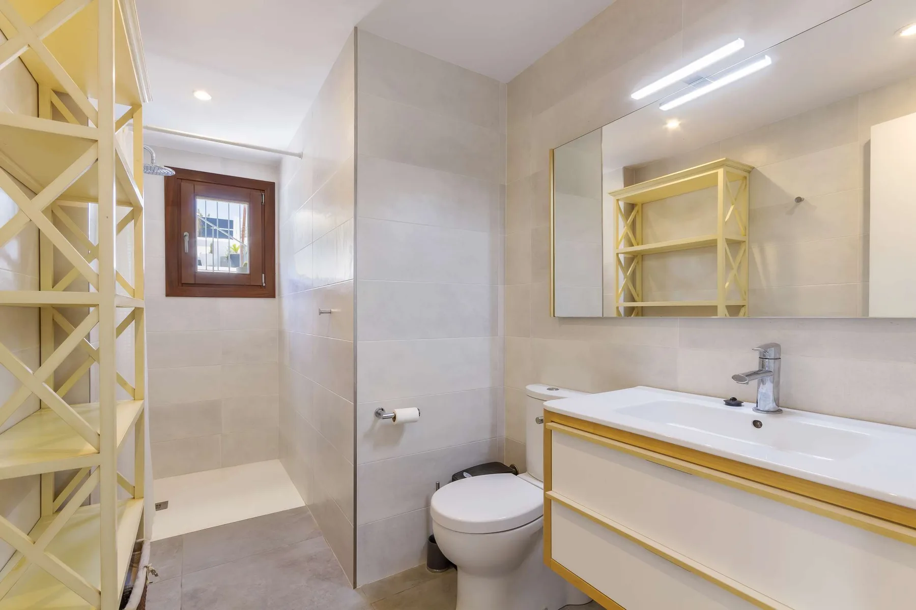 A bathroom with a sink, toilet, and open shelving.
