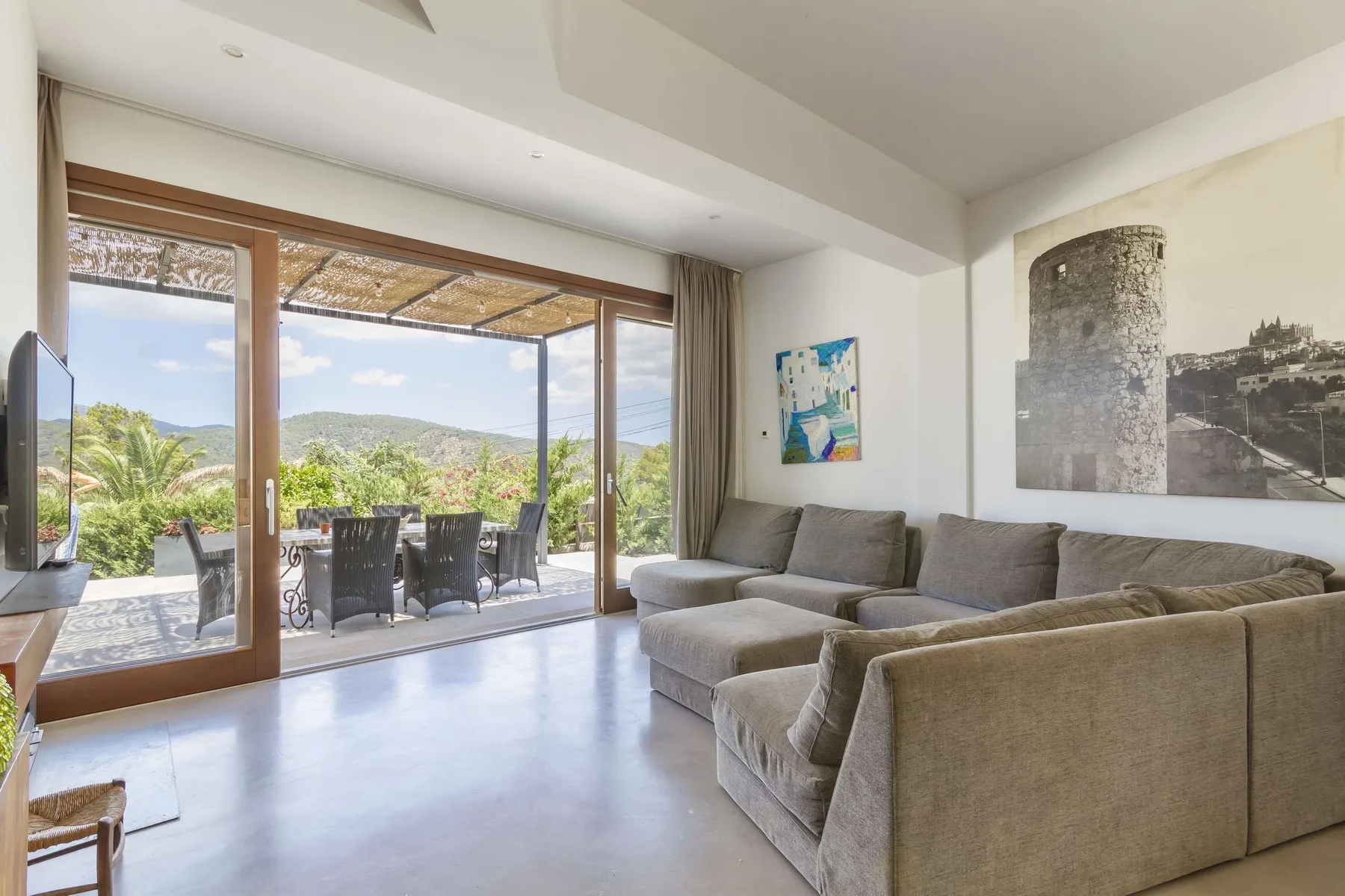 A bright living room with seating beside large glass doors opening onto a patio.