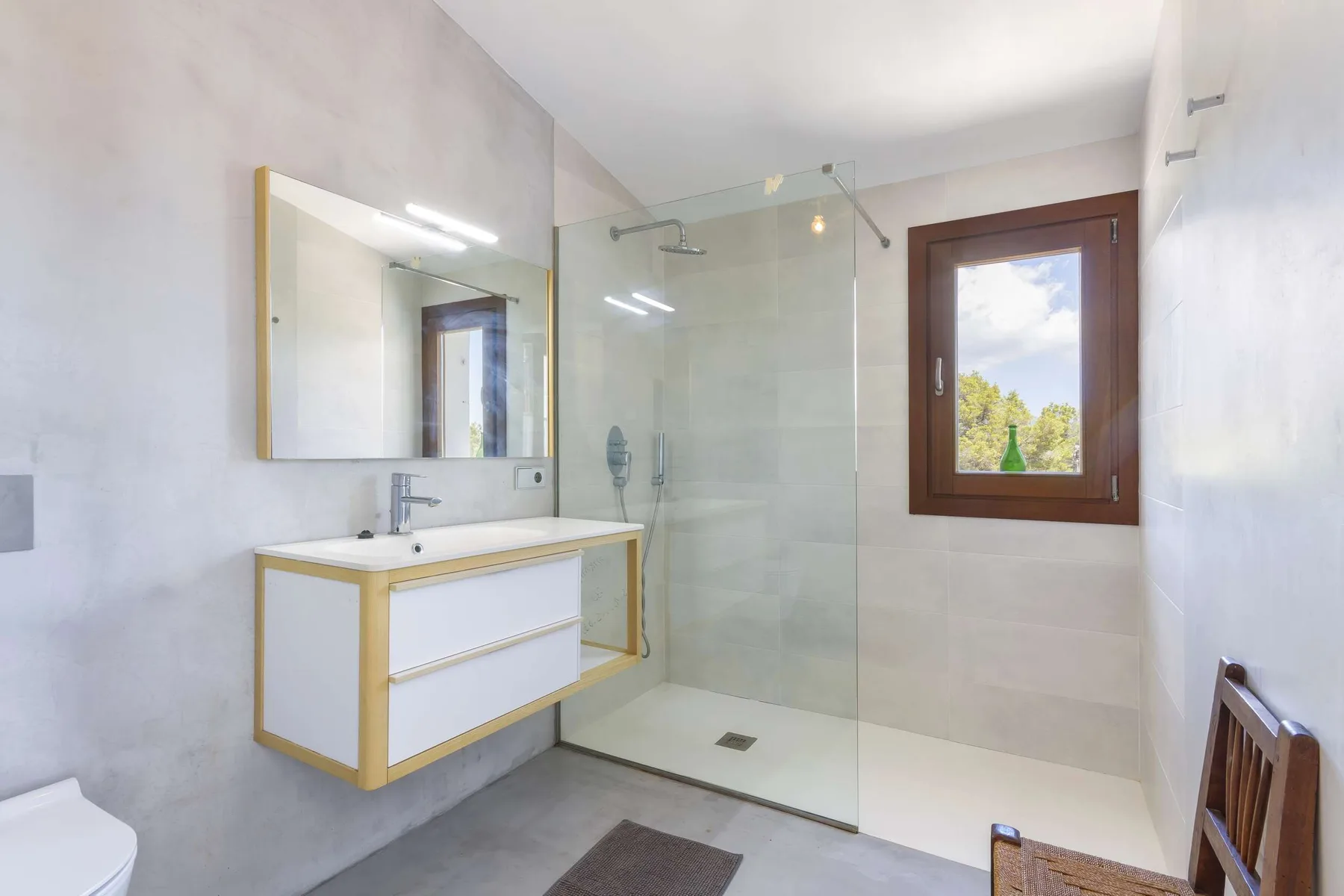A bright bathroom with a floating vanity, mirror, and glass shower.