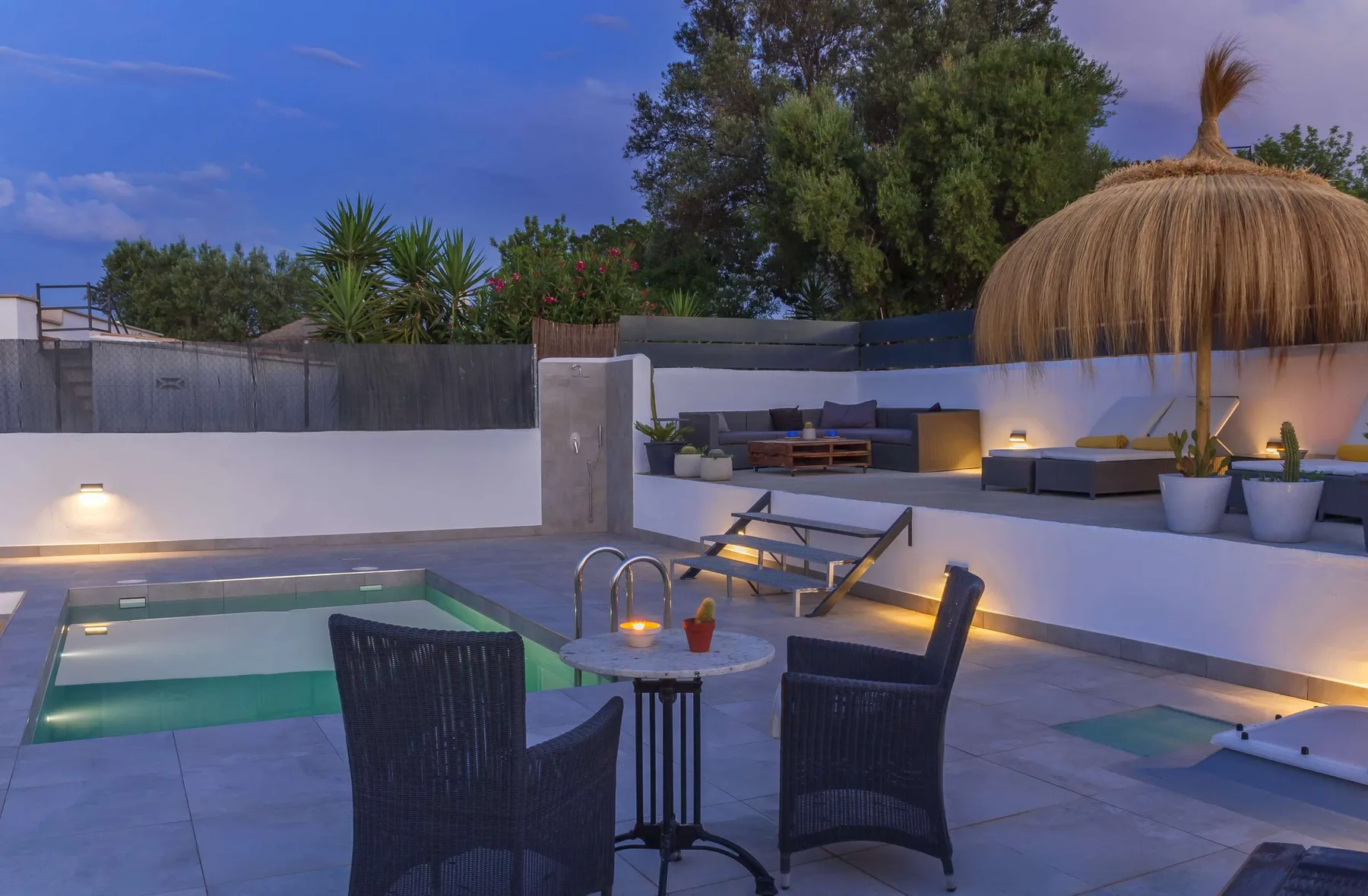 An outdoor pool area with dark seating and illuminated lounge spaces.
