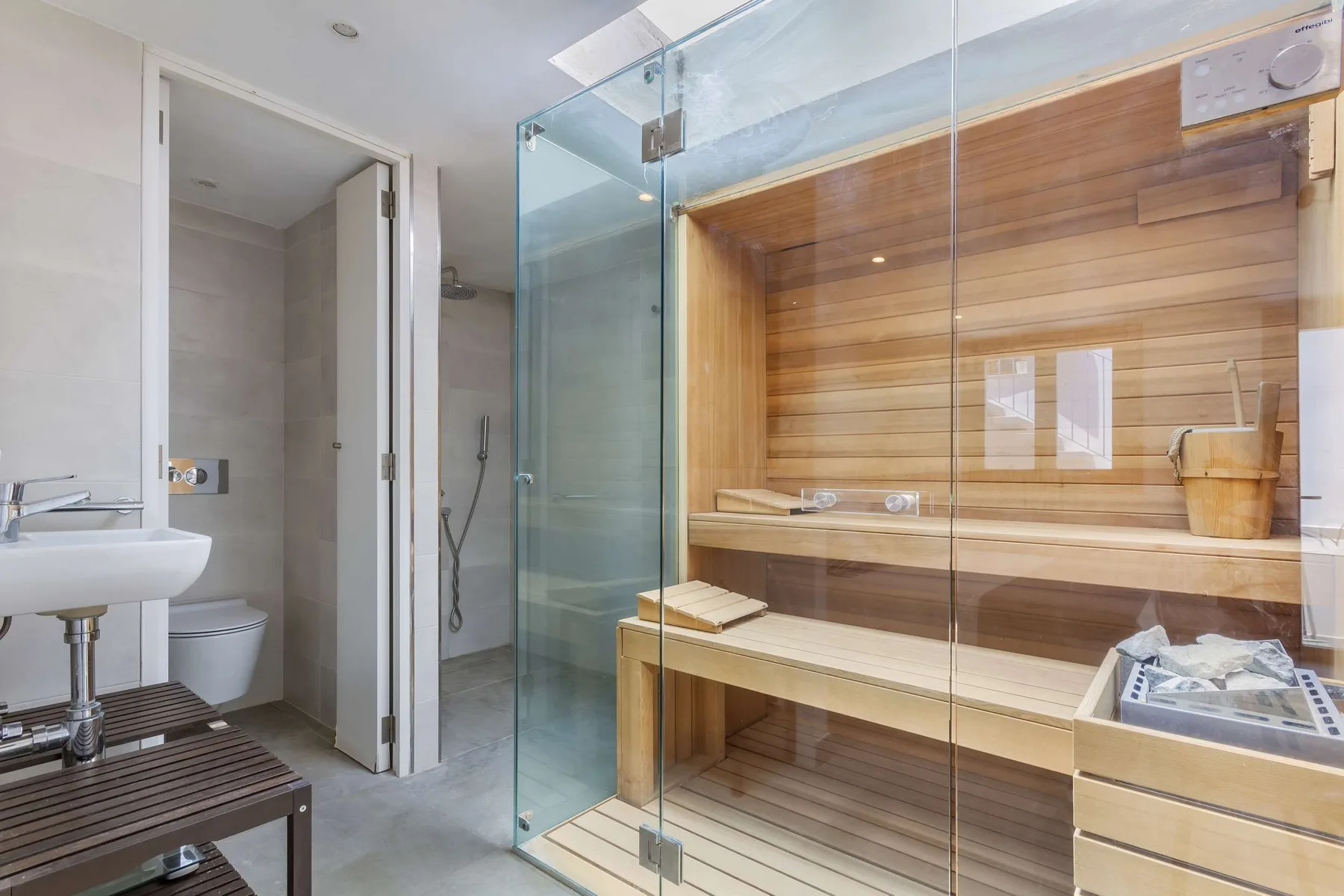 A bathroom with a glass-enclosed shower and a wooden sauna.