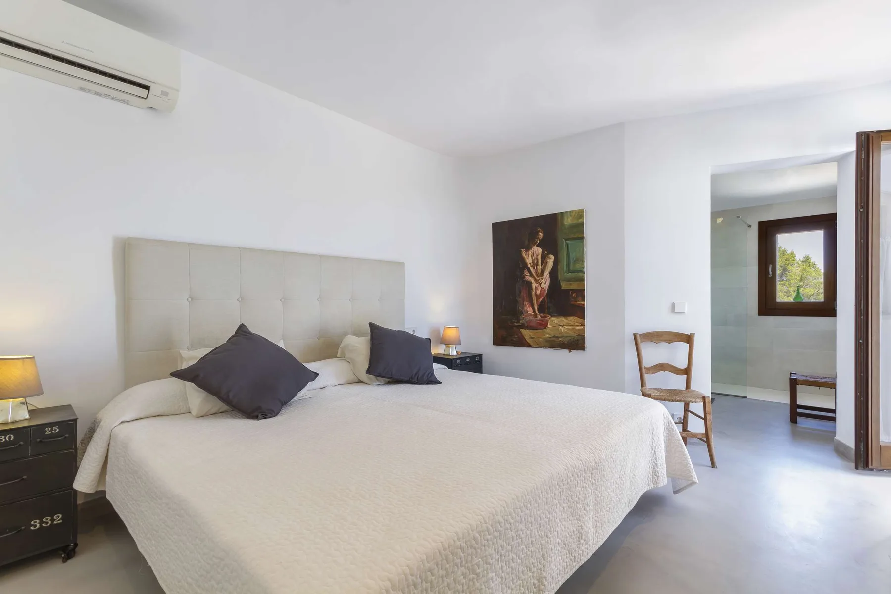 A bright bedroom with a large bed and an open doorway to an adjoining space.
